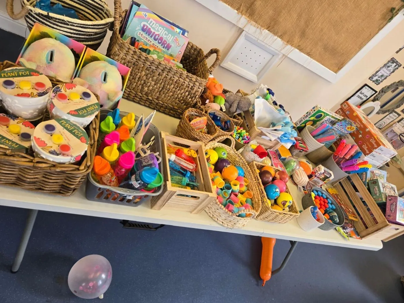 A long table covered in toys, soft toys, bubbles and baskets of prizes