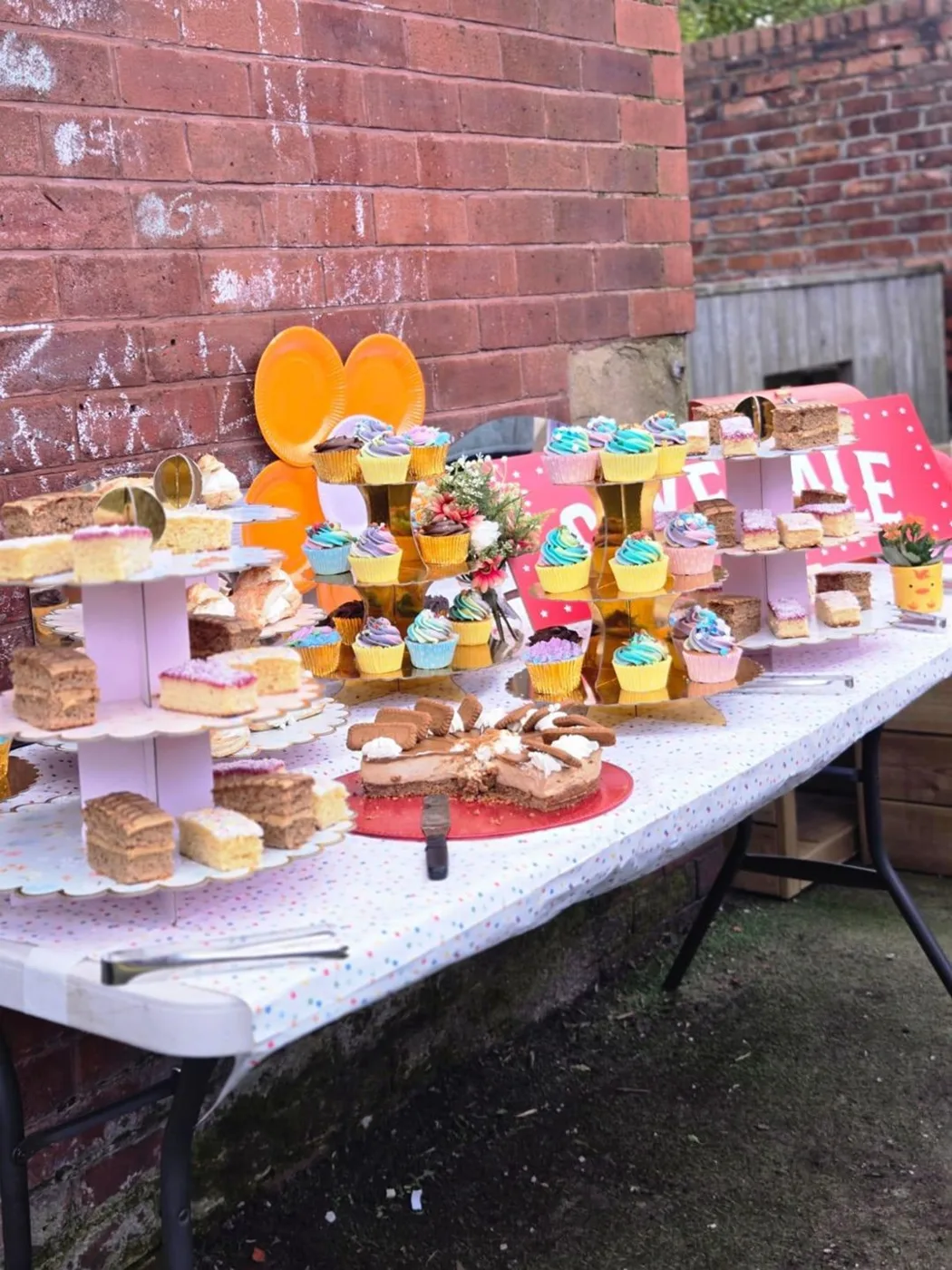 A table of homemade cupcakes, traybakes and cakes on tiered stands