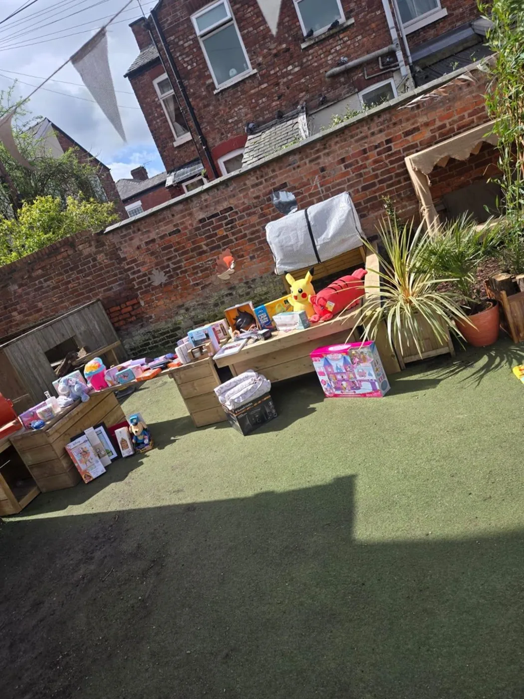 Tables of wrapped tombola prizes and toys laid out on the nursery's garden lawn under bunting