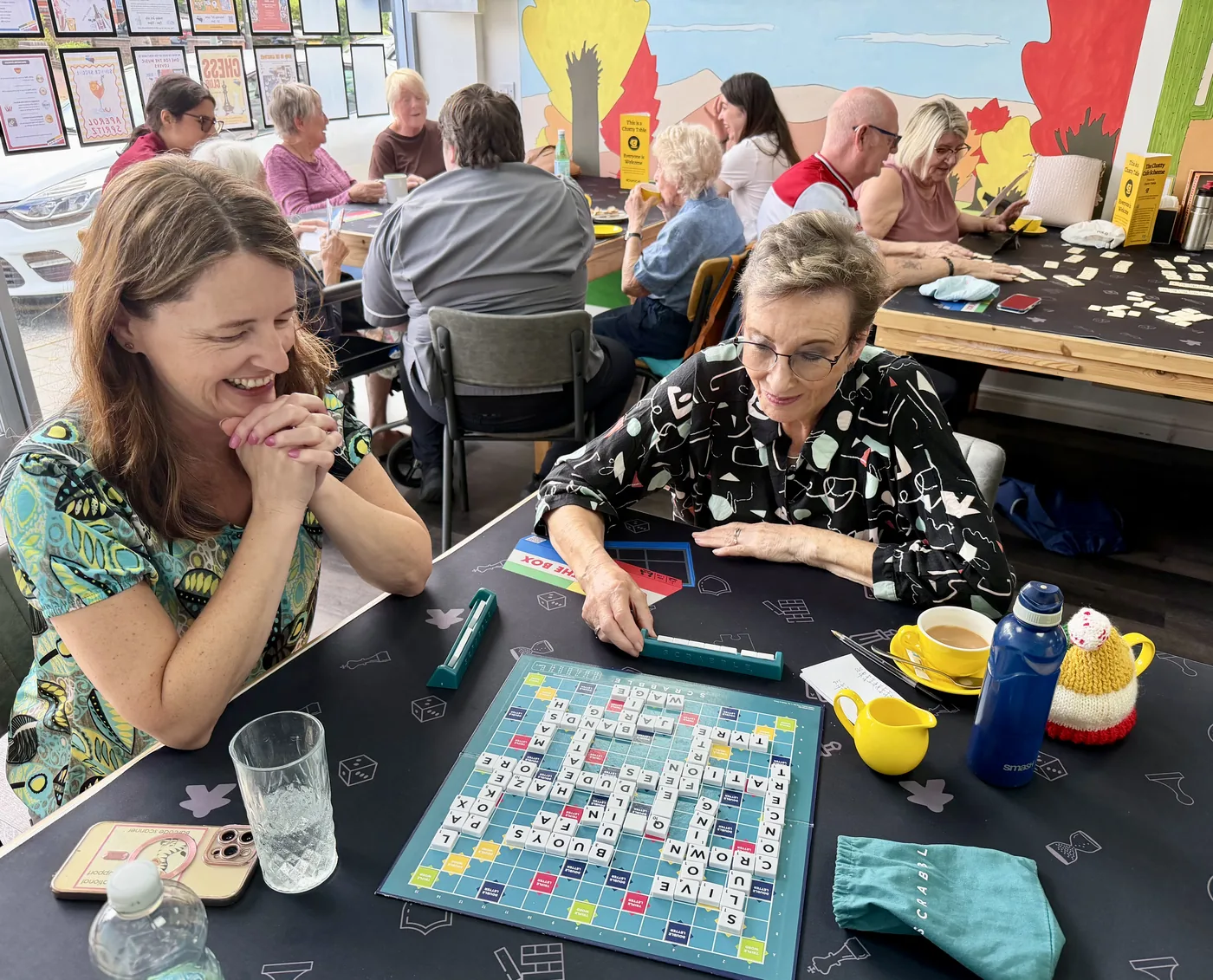 People playing Scrabble at a table in the café, with other tables occupied behind them