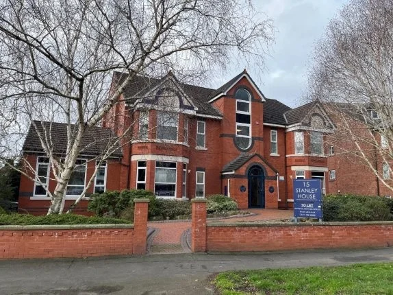 Stanley House, a red-brick building with gables and bay windows behind a low brick wall on Ladybridge Road, Cheadle Hulme, with a Stanley House sign at the entrance